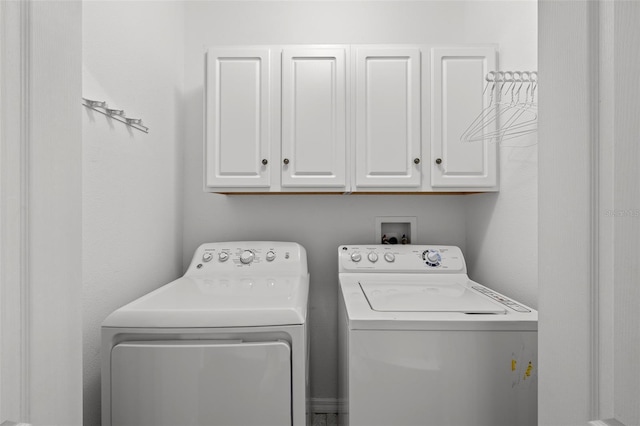 clothes washing area featuring washing machine and clothes dryer and cabinet space