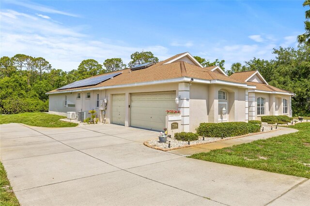 7206 River Country Dr, Weeki Wachee, FL 34607 - view of front of property with an attached garage, concrete driveway, a front lawn, solar panels, and stucco siding