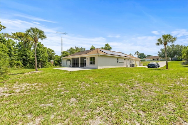 7206 River Country Dr, Weeki Wachee, FL 34607 - rear view of house featuring a sunroom, roof mounted solar panels, a lawn, a patio, and stucco siding