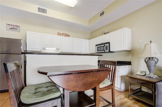 13235 Gulf Blvd Unit 402, Saint Petersburg, FL 33708 - kitchen featuring stainless steel appliances, white cabinetry, dark countertops, and light tile patterned floors