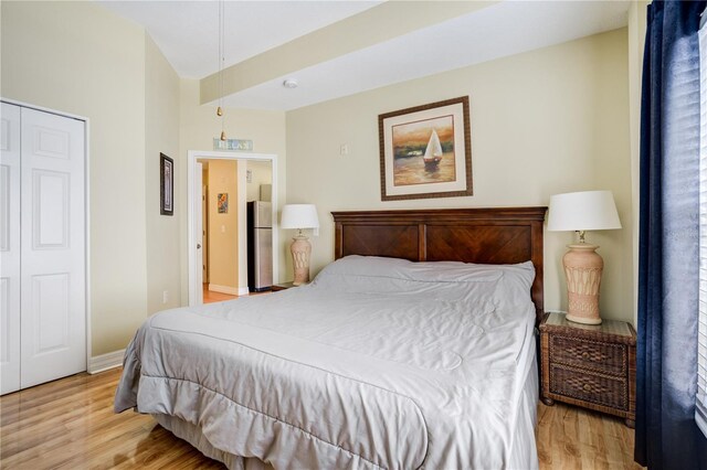 13235 Gulf Blvd Unit 402, Saint Petersburg, FL 33708 - bedroom featuring light wood-type flooring, baseboards, freestanding refrigerator, and a closet