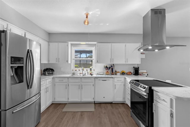 4727 Wales St, Lake Wales, FL 33859 - kitchen featuring appliances with stainless steel finishes, island exhaust hood, a sink, a peninsula, and light wood-style flooring