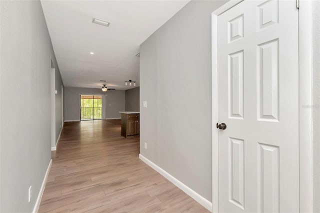 hall featuring light wood-style floors and baseboards