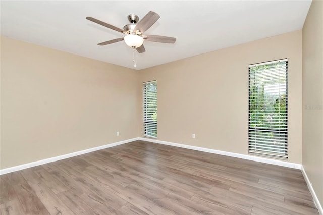 empty room with wood finished floors, baseboards, and a ceiling fan