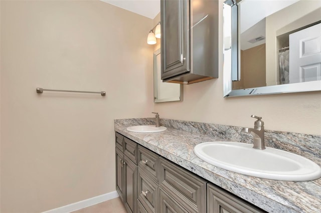 bathroom with double vanity, tile patterned floors, and baseboards