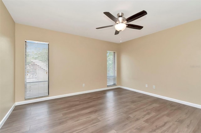 spare room with a ceiling fan, wood finished floors, and baseboards