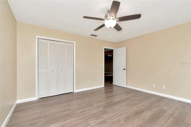 unfurnished bedroom with wood finished floors, baseboards, and a closet