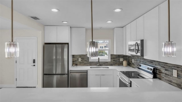 281 44th Ave, St Pete Beach, FL 33706 - kitchen with appliances with stainless steel finishes, a sink, light countertops, white cabinetry, and decorative backsplash