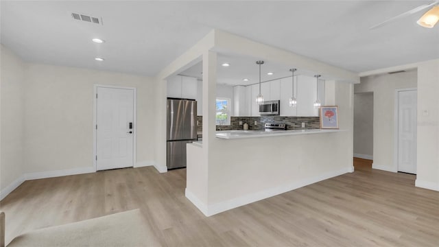 281 44th Ave, St Pete Beach, FL 33706 - kitchen with stainless steel appliances, white cabinets, light wood-style flooring, decorative backsplash, and baseboards
