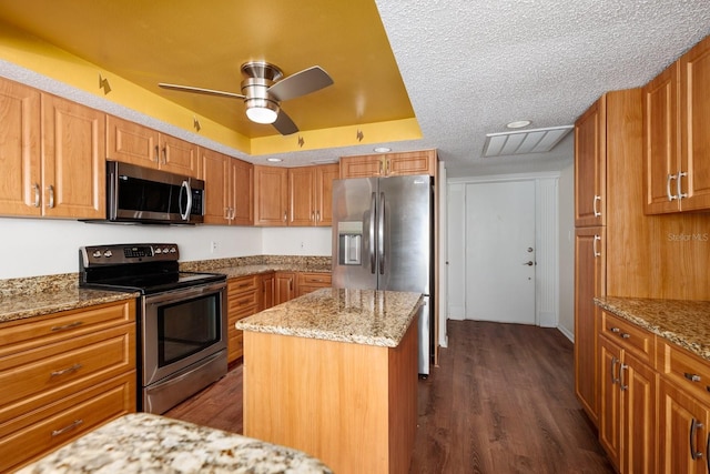 17408 Gulf Blvd Unit 203, Redington Shores, FL 33708 - kitchen with stainless steel appliances, ceiling fan, dark wood-style flooring, light stone counters, and a center island