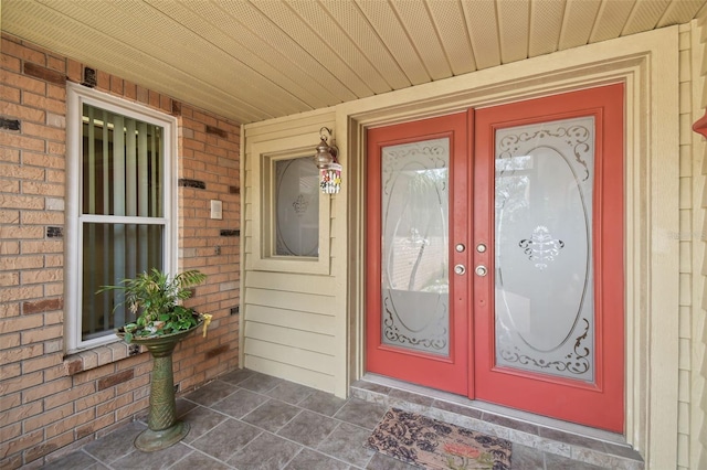 property entrance featuring brick siding, french doors, and covered porch