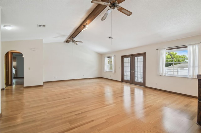 unfurnished living room featuring a ceiling fan, arched walkways, baseboards, light wood-style flooring, and french doors