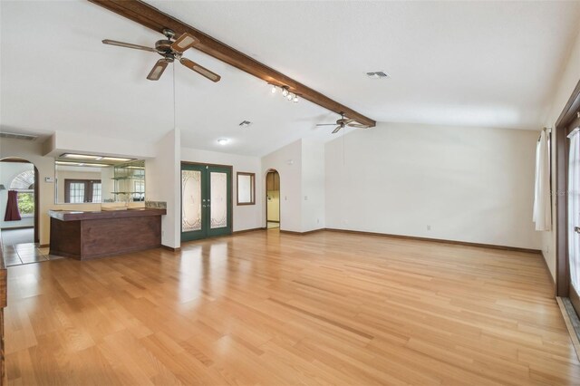 unfurnished living room with ceiling fan, arched walkways, french doors, and plenty of natural light