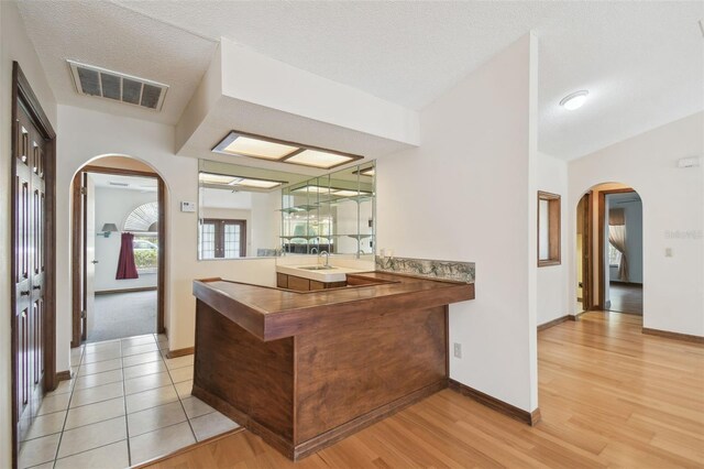 bar with arched walkways, light wood finished floors, and baseboards