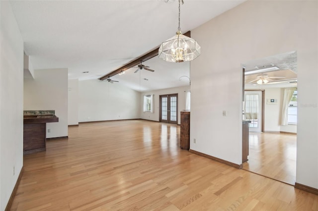 unfurnished living room featuring ceiling fan, light wood-type flooring, baseboards, and a chandelier
