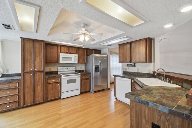 kitchen featuring white appliances, a sink, a ceiling fan, light wood-type flooring, and a peninsula