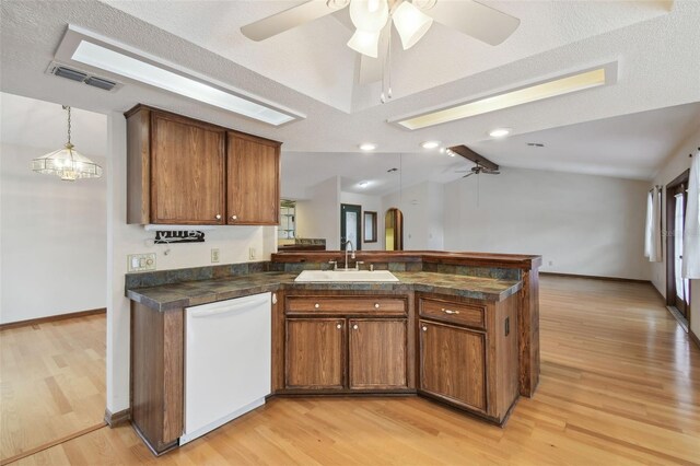 kitchen featuring white dishwasher, a sink, a peninsula, a ceiling fan, and brown cabinetry