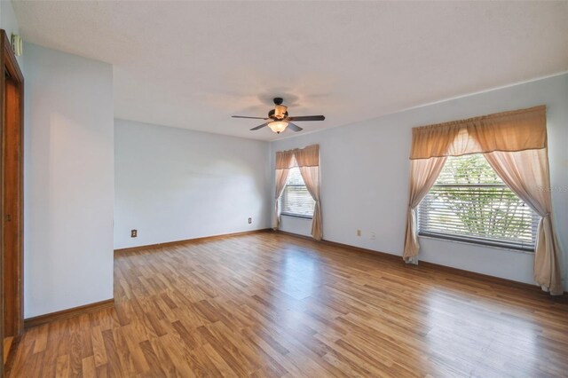 spare room featuring a ceiling fan, light wood-type flooring, and baseboards