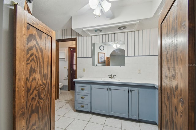 bathroom with a ceiling fan, tile patterned flooring, toilet, vanity, and a textured ceiling