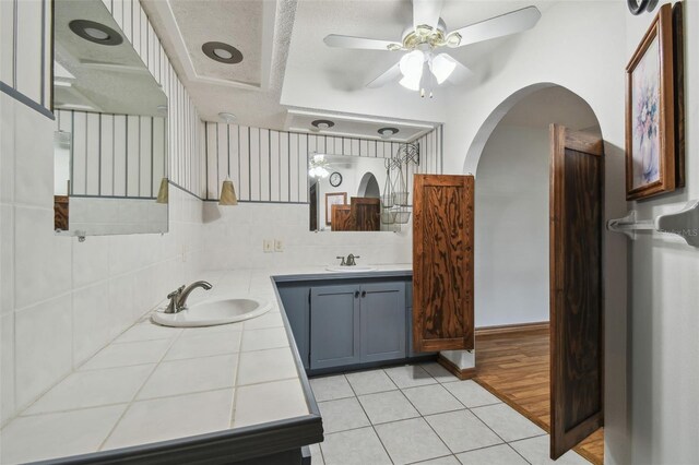 full bathroom with two vanities, a ceiling fan, and tile patterned floors