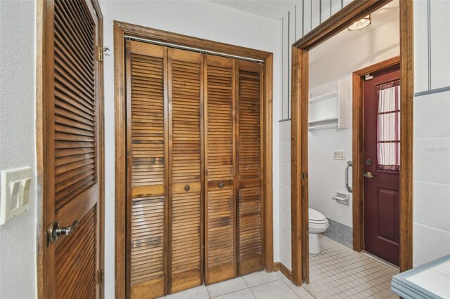 bathroom with a closet, tile patterned floors, and toilet