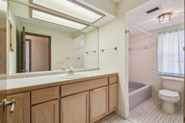 bathroom featuring tile patterned flooring, toilet, bathing tub / shower combination, and vanity