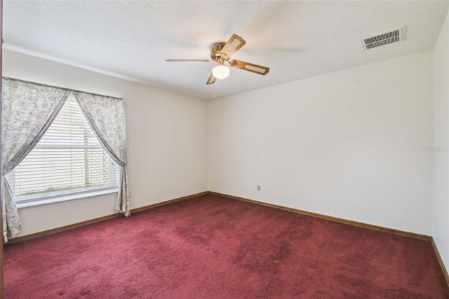 spare room featuring dark carpet, ceiling fan, a textured ceiling, and baseboards