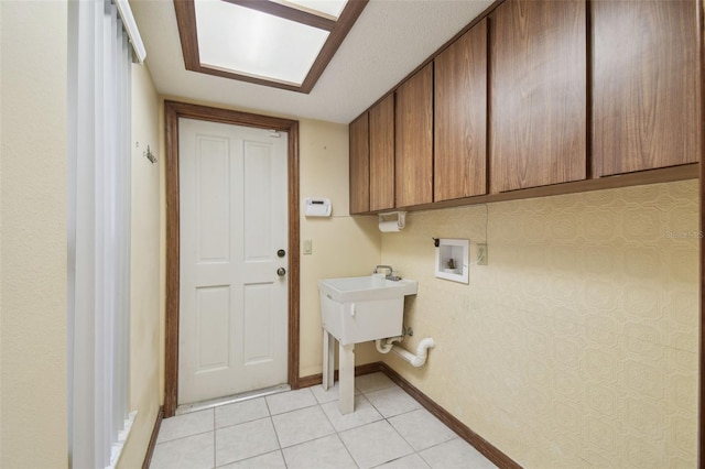 clothes washing area featuring hookup for a washing machine, cabinet space, baseboards, and light tile patterned flooring