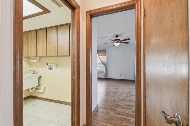 corridor featuring baseboards, light wood-style flooring, and a desk