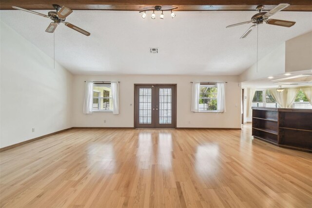 unfurnished living room with a ceiling fan, lofted ceiling, light wood-style flooring, and baseboards