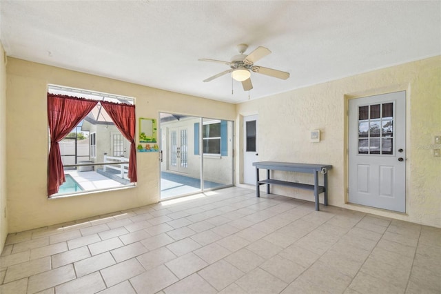 spare room with a ceiling fan, a textured wall, and tile patterned flooring