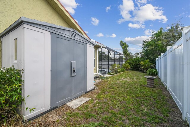 view of yard featuring a shed, an outdoor structure, and glass enclosure