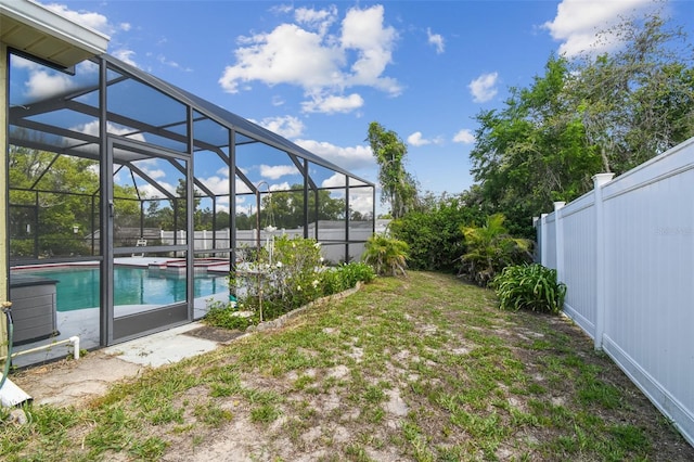 view of yard with fence, a pool with connected hot tub, and glass enclosure