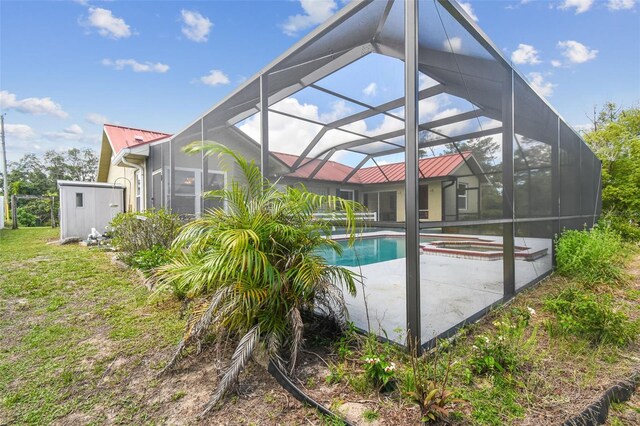 view of pool with a patio area, glass enclosure, and a pool with connected hot tub
