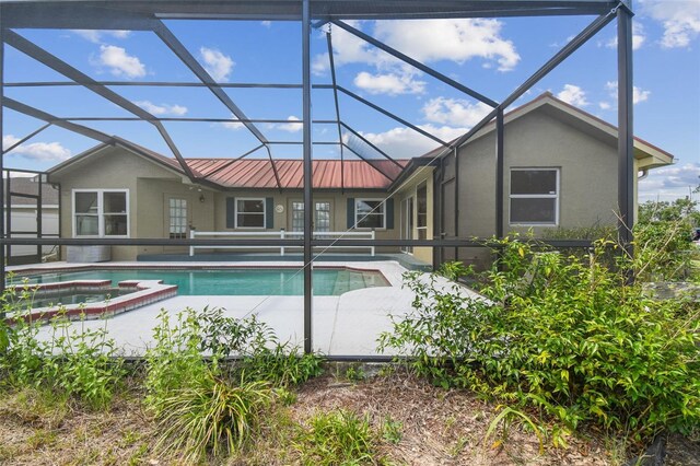 view of swimming pool featuring a patio, glass enclosure, and a pool with connected hot tub