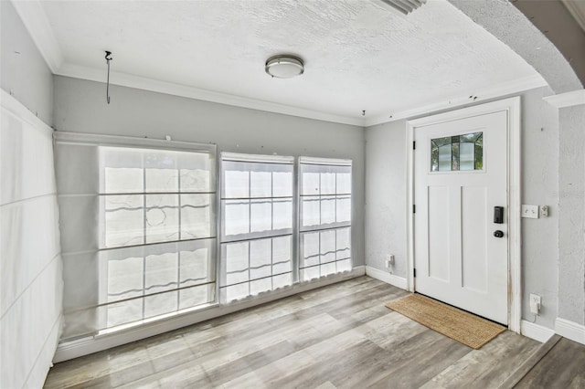 2018 21st St S, Saint Petersburg, FL 33712 - entrance foyer featuring wood finished floors, crown molding, baseboards, a textured ceiling, and arched walkways