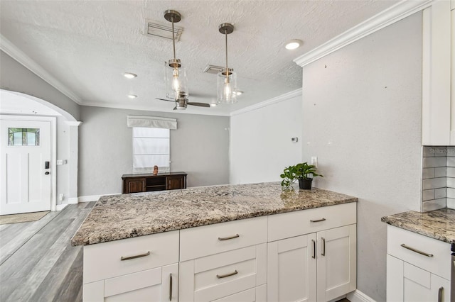 2018 21st St S, Saint Petersburg, FL 33712 - kitchen featuring a textured ceiling, ornamental molding, light wood-style floors, white cabinets, and light stone counters