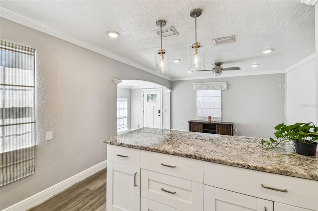 2018 21st St S, Saint Petersburg, FL 33712 - kitchen with baseboards, dark wood-style floors, arched walkways, white cabinets, and crown molding