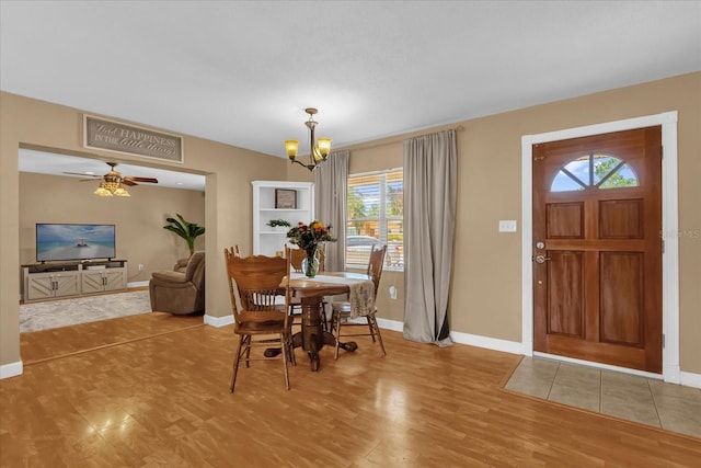 dining room featuring wood finished floors, healthy amount of natural light, baseboards, and a chandelier
