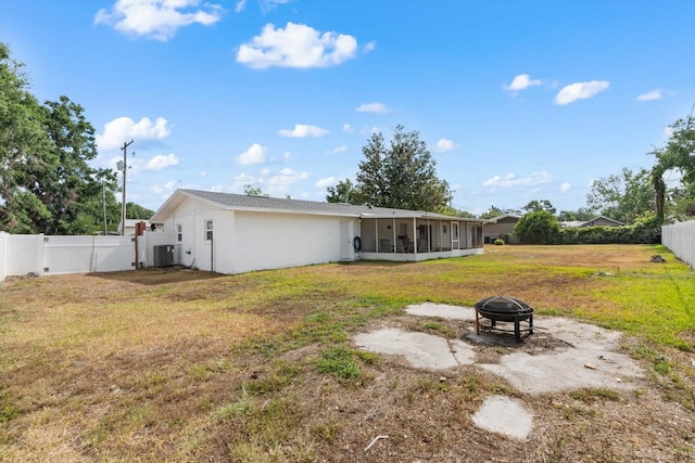 back of property with an outdoor fire pit, a sunroom, and central AC