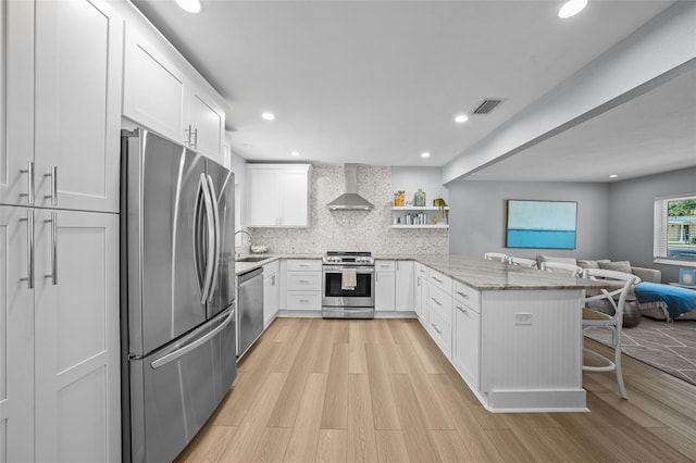 608 Betmor Ln, Palm Harbor, FL 34683 - kitchen featuring appliances with stainless steel finishes, wall chimney range hood, a peninsula, open floor plan, and a breakfast bar area