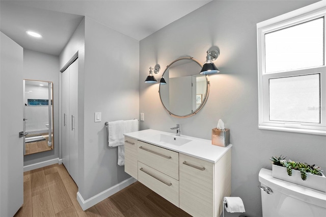 608 Betmor Ln, Palm Harbor, FL 34683 - bathroom with wood finished floors, toilet, baseboards, and vanity