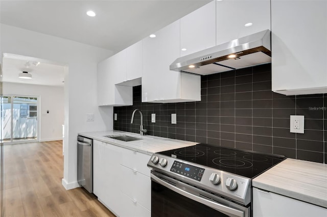 3151 6th Ave S, Saint Petersburg, FL 33712 - kitchen featuring stainless steel appliances, ventilation hood, a sink, white cabinetry, and decorative backsplash