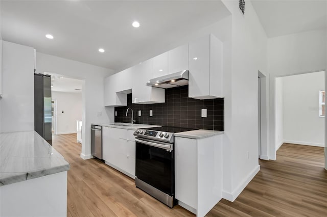 3151 6th Ave S, Saint Petersburg, FL 33712 - kitchen with stainless steel appliances, exhaust hood, a sink, light countertops, and backsplash