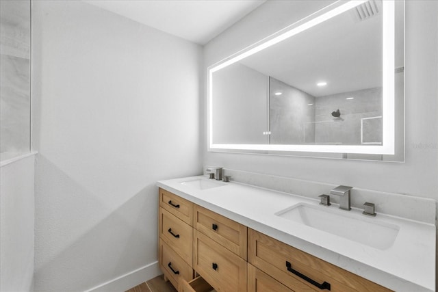 full bath with a tile shower, double vanity, and baseboards