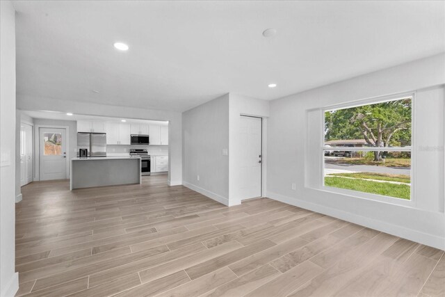 unfurnished living room with baseboards, recessed lighting, and light wood-type flooring