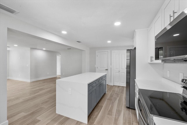 kitchen featuring stainless steel appliances, a barn door, white cabinets, light countertops, and recessed lighting