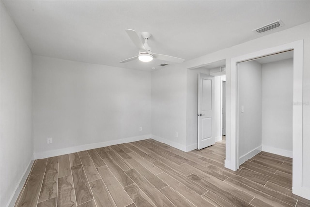 empty room with light wood-type flooring, a ceiling fan, and baseboards