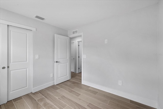 unfurnished bedroom featuring baseboards, wood tiled floors, and a closet