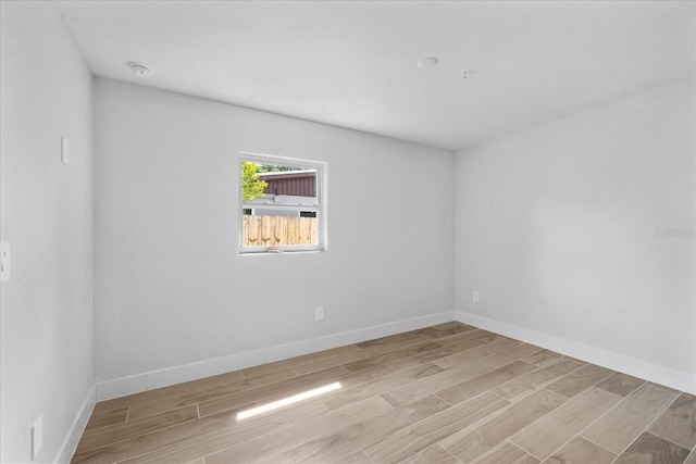 spare room with wood finished floors, baseboards, and a smoke detector